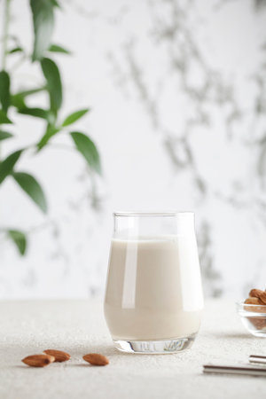 Vegan almond milk in glass with nuts on white background. Copy space. Healthy vegetarian food. selective focus. Non dairy alternative milkの写真素材