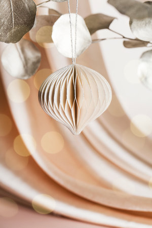 Christmas honeycomb paper decor on golden branch on beige background with textile and bokeh. Seasonal holidays, greeting card, eco friendly holiday.の写真素材