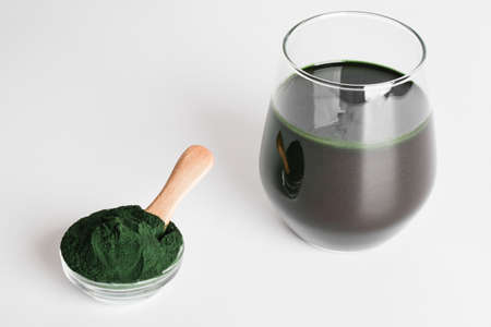 fresh green drink with spirulina in glass, spirulina powder with spoon on white background. useful habits, self care and healthy lifestyle.copy spaceの写真素材