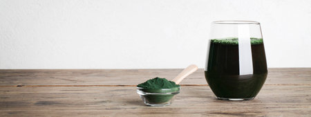 fresh green drink with spirulina in glass, spirulina powder with spoon on wooden background. self care and healthy lifestyle.copy space bannerの写真素材