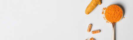 health care lifestyle concept. spoon with turmeric powder, root and pills on blue background. flat lay top view copy space bannerの写真素材