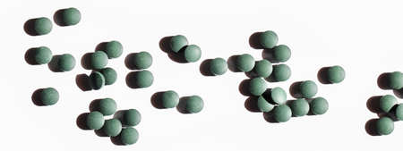 natural additives and superfoods. green spirulina algae pills on white background with shadow....
