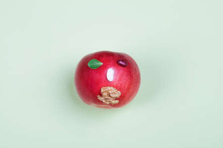 healthy food. Top view of apple with beans and nut in form of face on green background. Vegan diet...