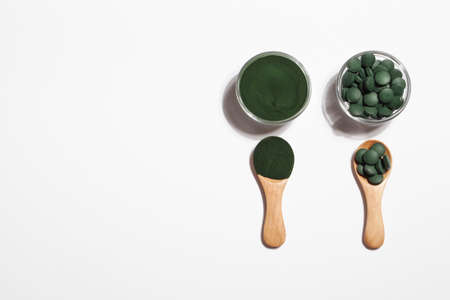 natural additives and superfood. green spirulina algae powder and pills in glass bowls on white background. healthy lifestyle concept. organic foodの写真素材