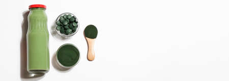 green smoothie in bottle and spirulina algae powder and pills in glass bowl on white background.useful habits,self care and healthy concept. bannerの写真素材