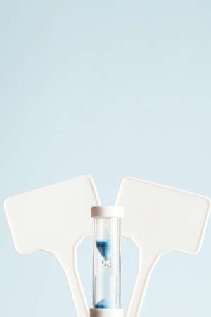 two blank sign with hourglass on blue background. copy space for your text. close up. comparison...