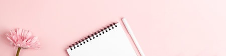 notebook and pen, flower on pink background. copy space top view banner. Woman workspace, business, study, freelancers and home office concept.の写真素材
