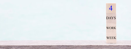 4 day working week words on wooden cube on blue background. reducing burnout and stress levels concept. copy space bannerの写真素材