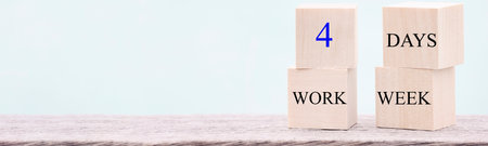 4 day working week words on wooden cube on blue background. reducing burnout and stress levels concept. copy space bannerの写真素材