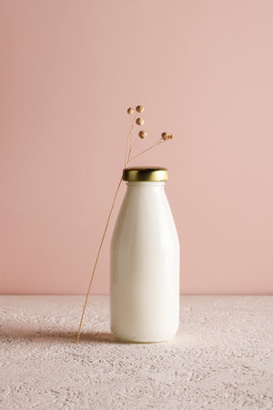 milk in bottle on beige background with plant. copyspace. Healthy food and lifestyle. Place for text. Dairy products conceptの写真素材