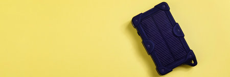cheapest source of electricity. power box, portable solar battery for phone on yellow background. innovative solutions concept. copy space bannerの写真素材