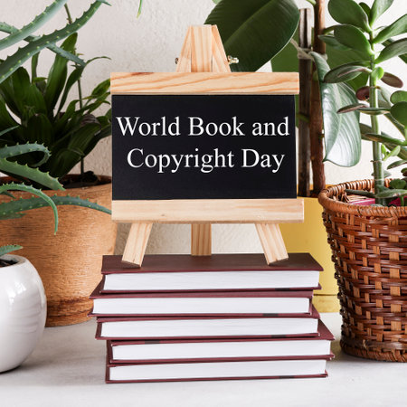 World Book and Copyright Day written on black board on stack of books on white background with...