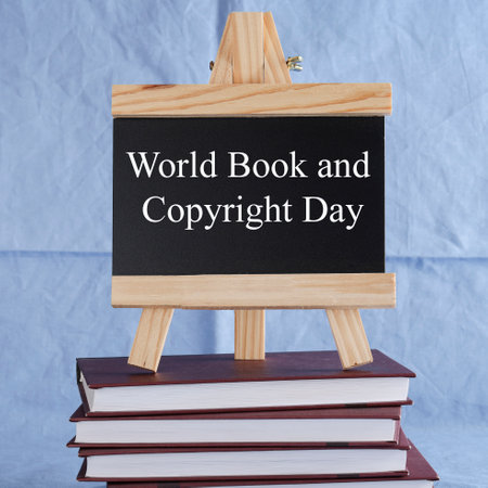 World Book and Copyright Day written on black board on stack of books on blue background. book holiday, education conceptの写真素材