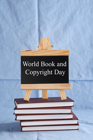World Book and Copyright Day written on black board on stack of books on blue background. book holiday, education conceptの写真素材