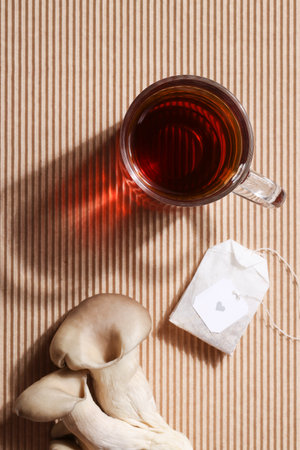 Natural medicine, reduce stress and improve immunity concept. Mushroom hot drink. Tea in glass mug with mushrooms on brown ribbed background.の写真素材