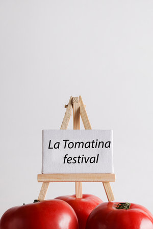 La Tomatina festival written on white board with red tomato on white background. famous tomato battle in the Spanish village of Bunyol concept.の写真素材