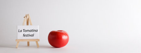 La Tomatina festival written on white board with red tomato on white background. famous tomato battle in the Spanish village of Bunyol concept. bannerの写真素材