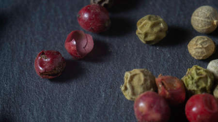 Pepper on a stone plate. Black background. Black stone. Close up. Macro