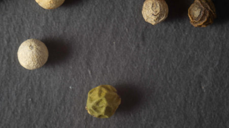 Pepper on a stone plate. Black background. Black stone. Close up. Macroの写真素材