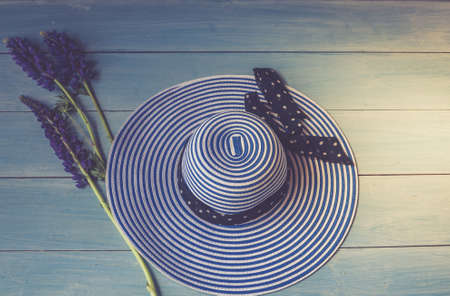 Women's accessories view from above. Conceptual image. Female hat and lupine flowers on a wooden background. Blue colourの写真素材