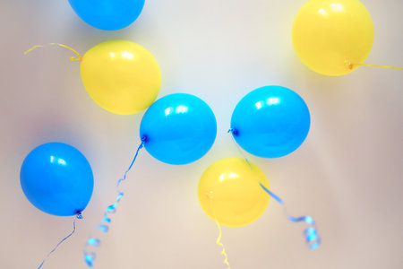 Colorful balloons on white background. birthday party concept. copyspace. yellow and blue helium air balloons under the ceilingの写真素材