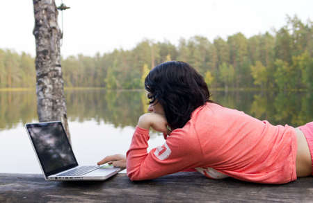 Woman with laptop near waterの写真素材