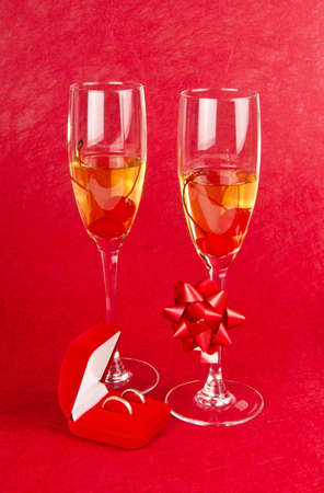 Two glass goblets with champagne and jewelry box on redの写真素材