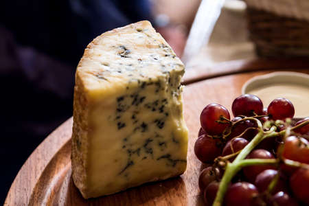 cheese on wooden plate with grapesの写真素材