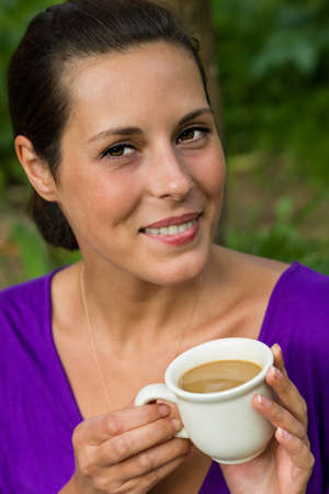 Beautiful young woman drinking coffee outdoorsの写真素材