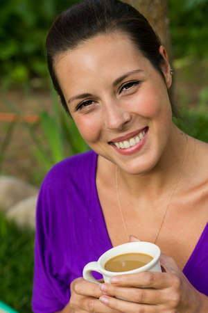 Beautiful young woman drinking coffee outdoorsの写真素材