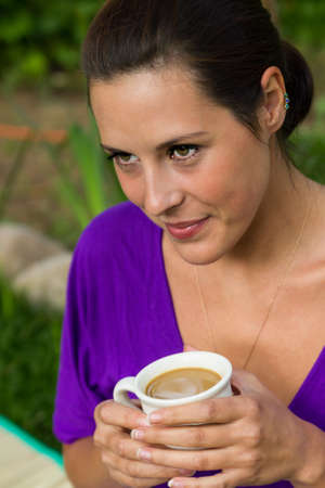 Beautiful young woman drinking coffee outdoorsの写真素材