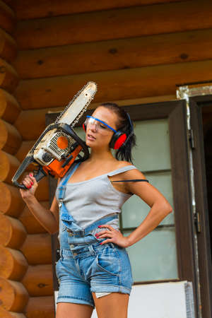 Pretty young woman builder with petrole-powered chain sawの写真素材