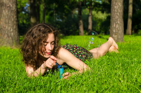 Young pretty woman blowing soap bubbles in parkの写真素材