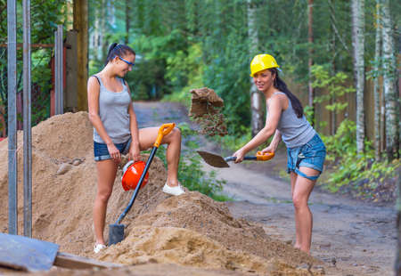 Pretty young woman builder digging a shovelの写真素材