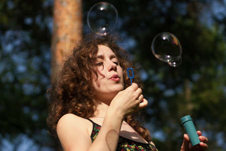 Young pretty woman blowing soap bubbles in parkの写真素材