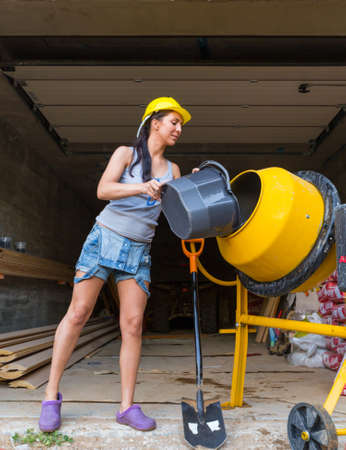 Pretty young woman builder and concrete mixer industrial temworkの写真素材