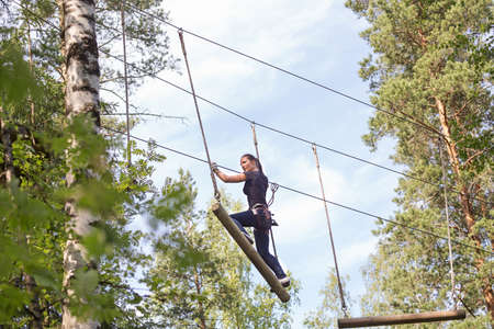 Young brave woman climbing in a adventure rope parkの写真素材