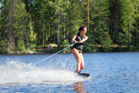 Young woman study riding wakeboarding on a lakeの写真素材