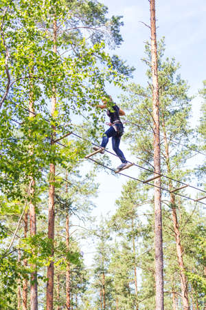 Young brave woman climbing in a adventure rope park