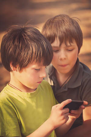 Child playing mobile phone outdoorsの写真素材