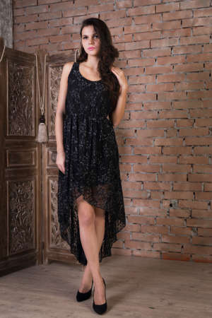 Woman in a black dress on a brick wallの写真素材