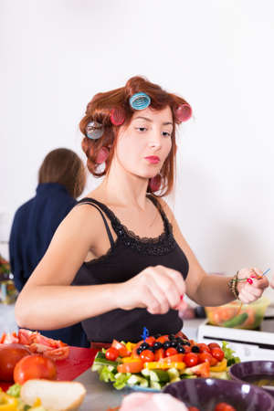 Young pretty woman housewife cooking with curlers on hairの写真素材