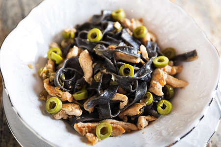 Black pasta with chicken and green olives tastyの写真素材
