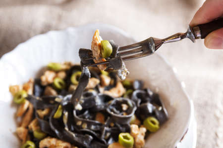 Black pasta with chicken and green olives tastyの写真素材