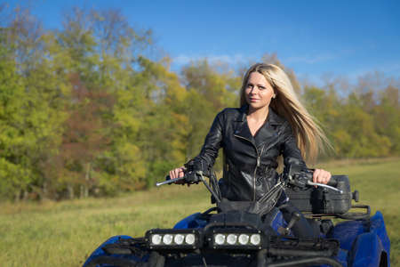 Elegant woman riding extreme quadrocycle ATV outdoorsの写真素材