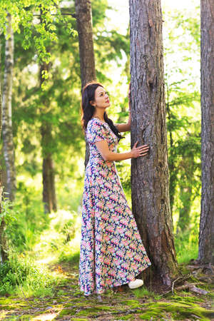 Young pretty woman poses showing dress summer outdoors in sunset lightの写真素材