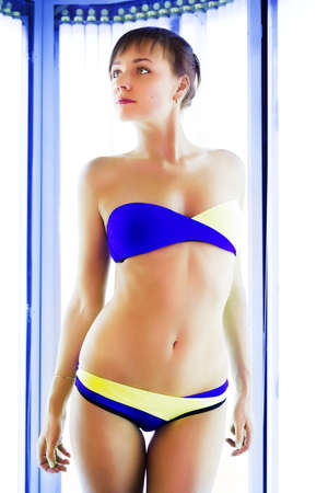 Pretty slim woman getting sun tan in solariumの写真素材
