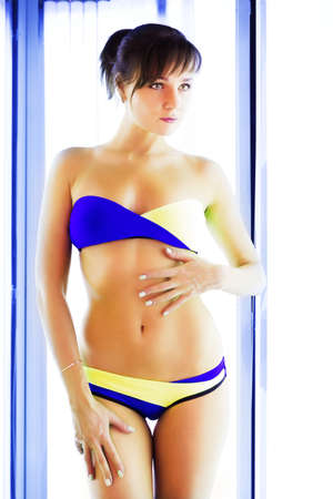 Pretty slim woman getting sun tan in solariumの写真素材