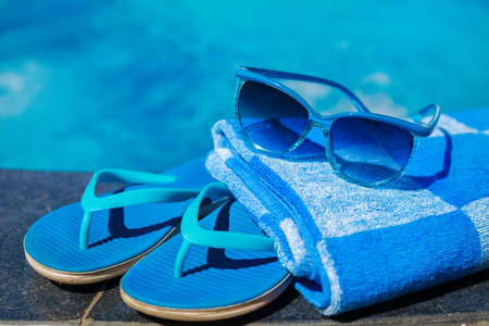 Blue slippers and sun glasses near swimming pool - holiday conceptの写真素材