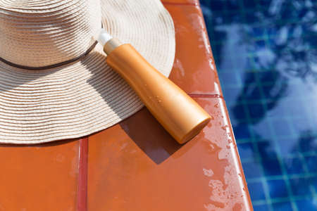Sunsscreen cream with straw hat near swimming pool - summer holiday conceptの写真素材